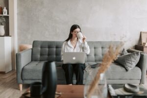 woman drinking coffee while working with laptop